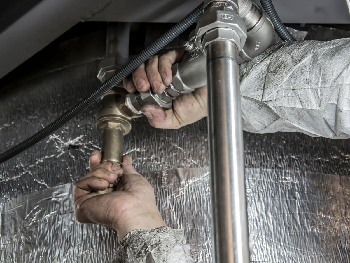A plumber tightening a pipe fitting