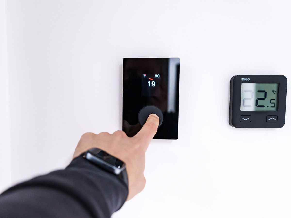 A thermostat being set on a wall